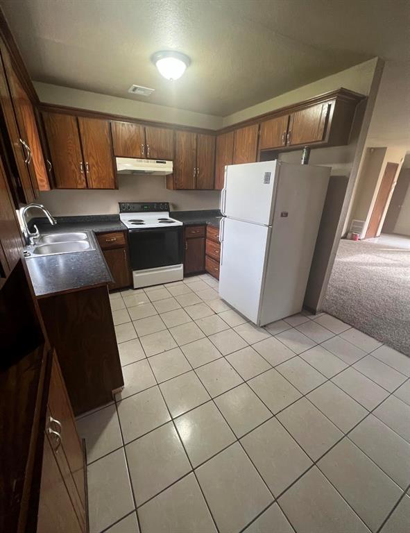 kitchen featuring light carpet, white appliances, and sink