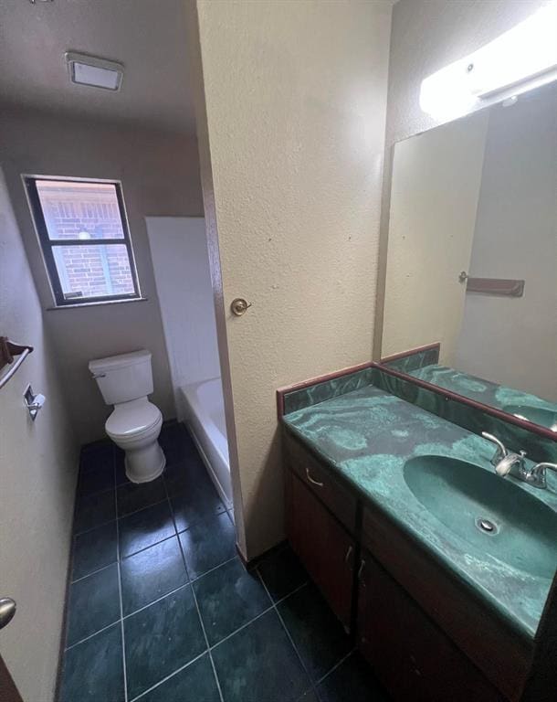 bathroom featuring tile patterned floors, vanity, toilet, and a bathing tub