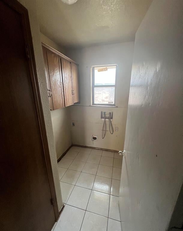 laundry area featuring cabinets, hookup for a washing machine, hookup for an electric dryer, a textured ceiling, and light tile patterned flooring