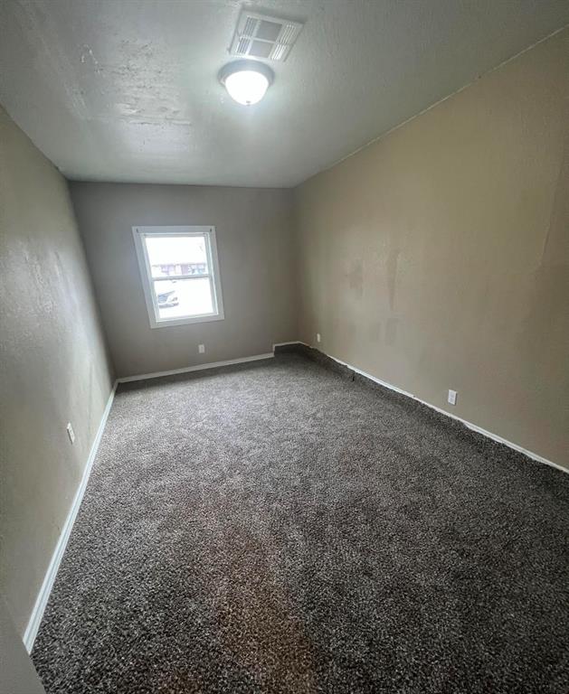 spare room featuring carpet floors and a textured ceiling