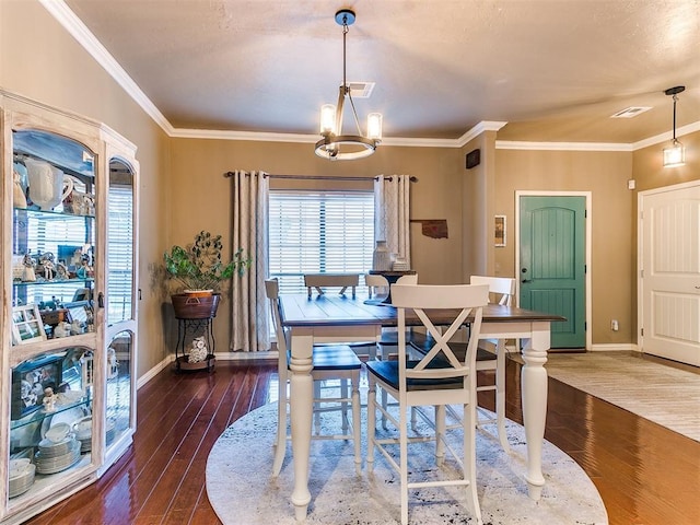 dining area featuring dark hardwood / wood-style floors, ornamental molding, and a chandelier