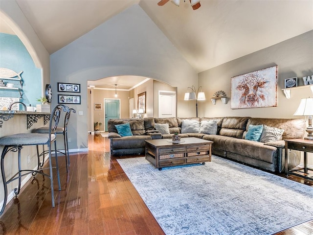 living room with ceiling fan, ornamental molding, dark wood-type flooring, and high vaulted ceiling