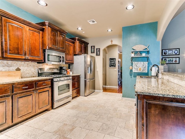 3393 Creek View Ct, Newcastle, OK 73065 - kitchen with appliances with stainless steel finishes, arched walkways, a sink, baseboards, and tasteful backsplash