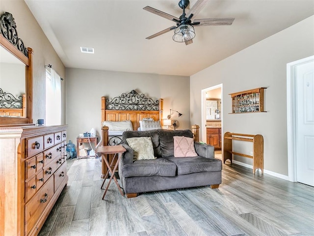 bedroom featuring ceiling fan, ensuite bathroom, and light hardwood / wood-style flooring