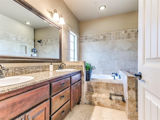 bathroom featuring tiled tub and vanity