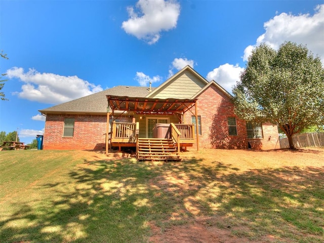 rear view of property featuring a pergola, a wooden deck, and a lawn