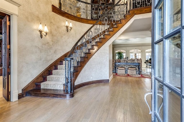 staircase featuring ornamental molding, wood-type flooring, and a high ceiling