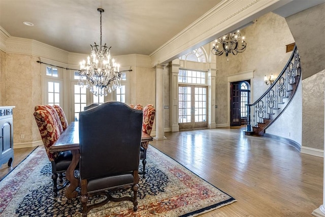 dining area featuring french doors, wood-type flooring, a chandelier, and decorative columns