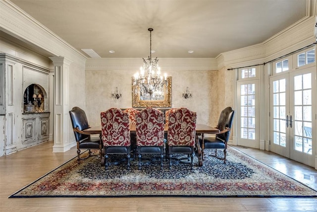 dining space with hardwood / wood-style floors, ornamental molding, french doors, and a chandelier