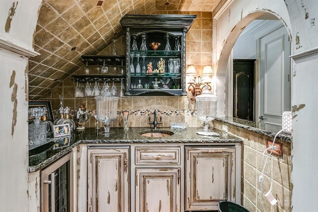 bar featuring dark stone countertops, sink, and tasteful backsplash