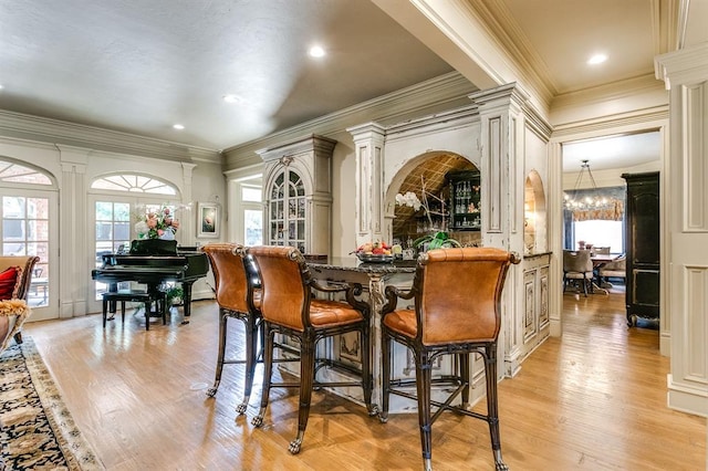 dining room with plenty of natural light, decorative columns, a chandelier, and light wood-type flooring