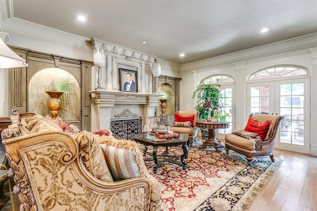 living area featuring crown molding, a high end fireplace, light hardwood / wood-style floors, and french doors