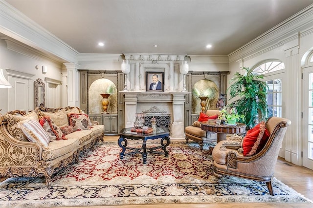 sitting room with light wood-type flooring, ornamental molding, a large fireplace, and ornate columns