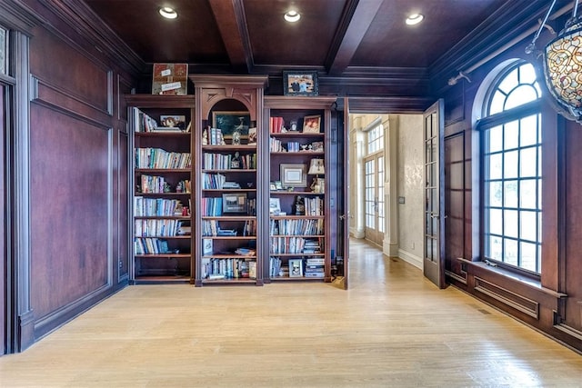 interior space with wood walls, beamed ceiling, coffered ceiling, crown molding, and light wood-type flooring