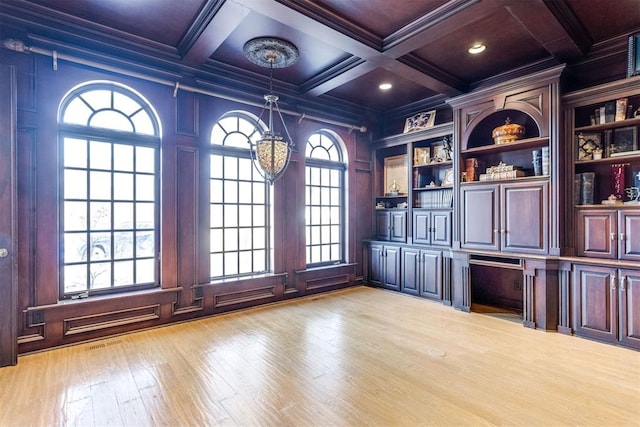 unfurnished office featuring beamed ceiling, ornamental molding, plenty of natural light, and light hardwood / wood-style flooring