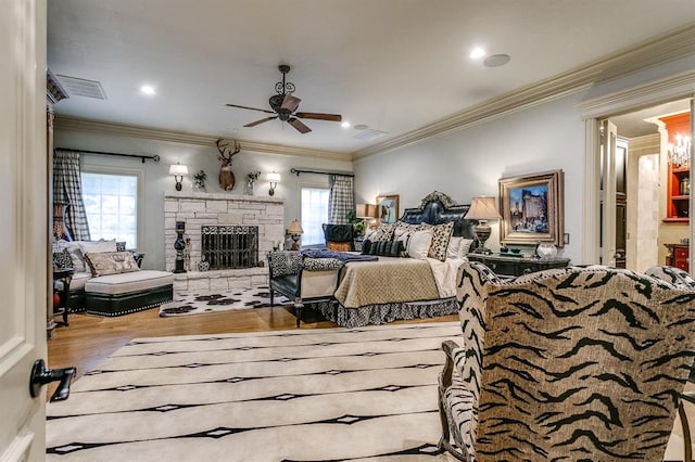 bedroom featuring ornamental molding, a fireplace, and light hardwood / wood-style floors