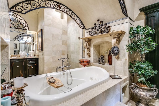 bathroom with vanity, tiled tub, and tile walls