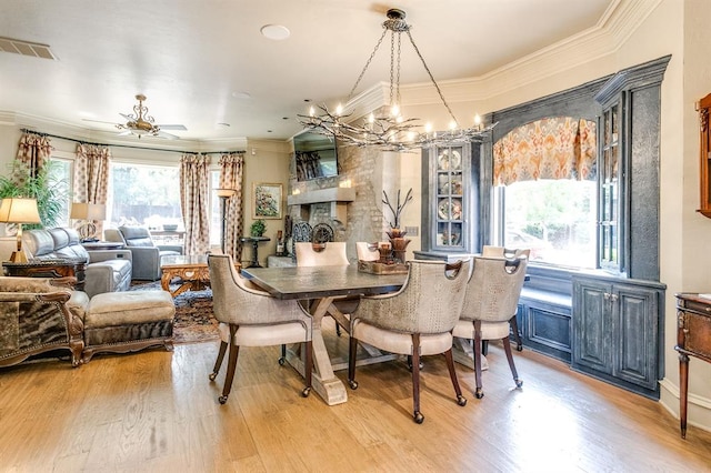 dining space with crown molding, ceiling fan with notable chandelier, and light hardwood / wood-style flooring