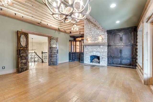 unfurnished living room featuring a fireplace, light hardwood / wood-style floors, and a chandelier