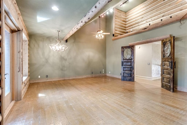 unfurnished living room with a high ceiling, ceiling fan with notable chandelier, and light wood-type flooring