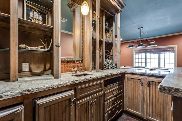 kitchen featuring crown molding, light stone countertops, sink, and hanging light fixtures