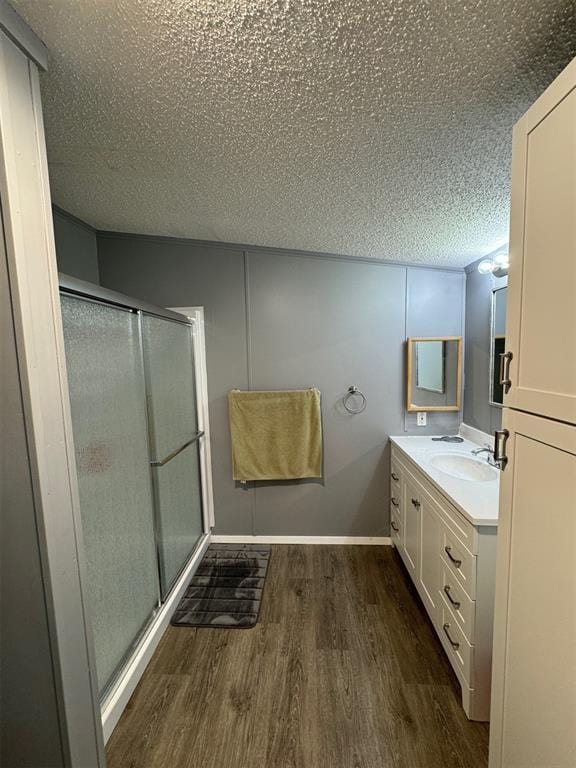 bathroom with a textured ceiling, vanity, hardwood / wood-style flooring, and a shower with shower door