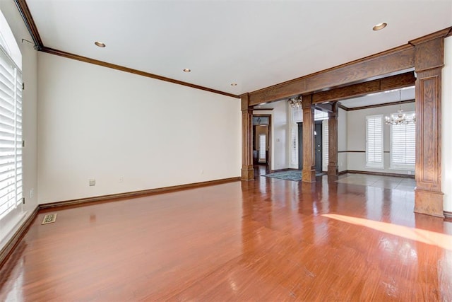 unfurnished room with decorative columns, a wealth of natural light, and hardwood / wood-style floors