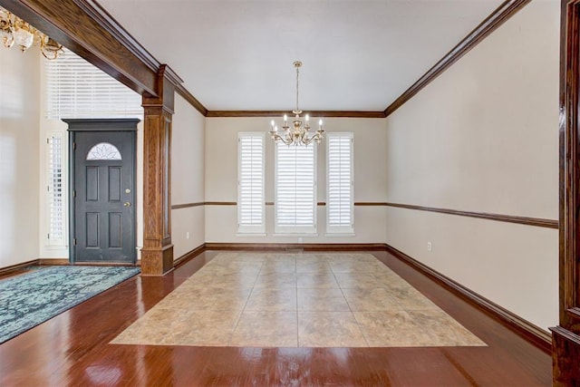 interior space featuring hardwood / wood-style floors, ornate columns, crown molding, and an inviting chandelier