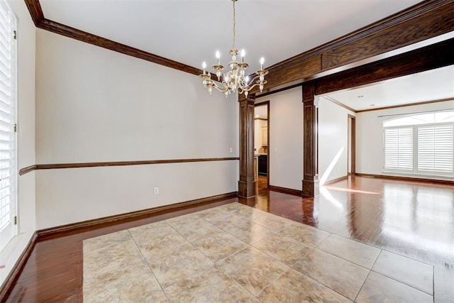 empty room featuring hardwood / wood-style flooring, ornate columns, crown molding, and a chandelier