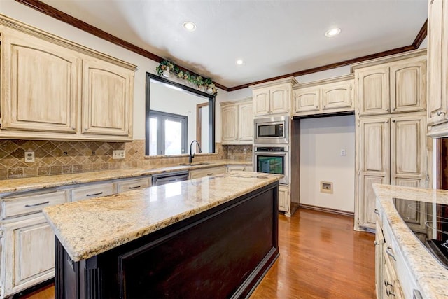 kitchen with stainless steel appliances, light stone counters, ornamental molding, and sink