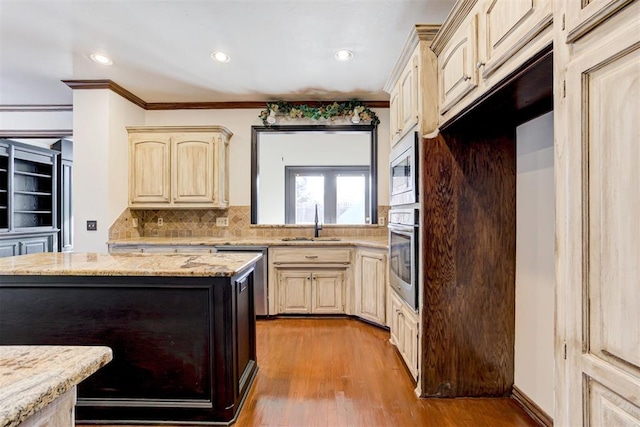 kitchen with appliances with stainless steel finishes, backsplash, light stone counters, sink, and light hardwood / wood-style floors