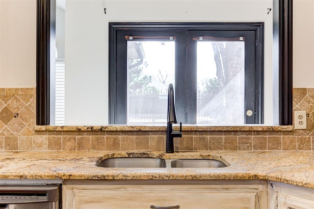 room details with stainless steel dishwasher, light brown cabinets, light stone counters, and sink