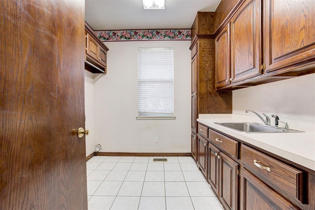 clothes washing area featuring light tile patterned floors and sink