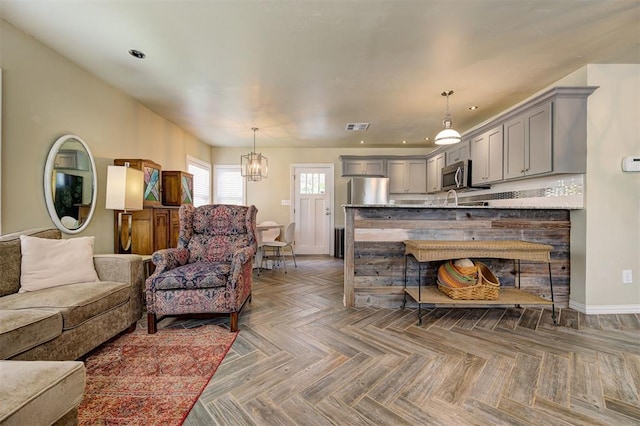 living room with dark parquet flooring and a notable chandelier