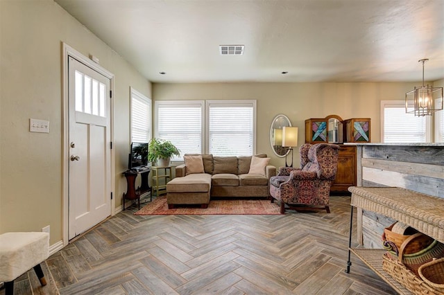 living room featuring parquet flooring, a healthy amount of sunlight, and a notable chandelier