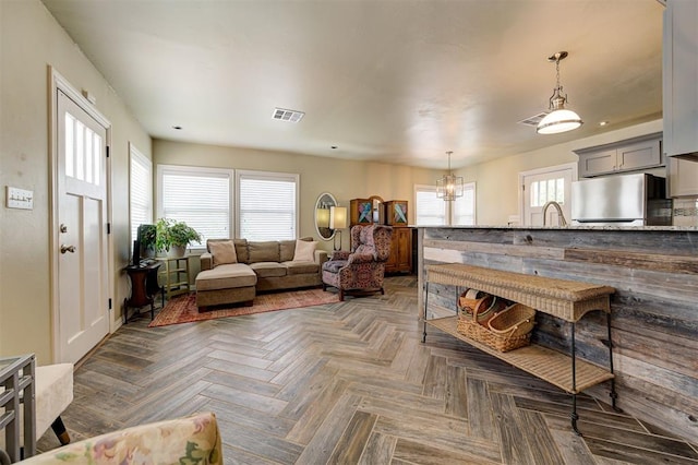 living room featuring a healthy amount of sunlight, dark parquet flooring, and a chandelier