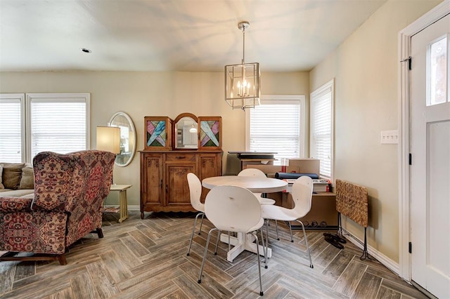 dining area featuring a chandelier, a healthy amount of sunlight, and parquet flooring