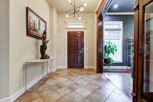 entryway with ornamental molding, light tile patterned floors, and a chandelier