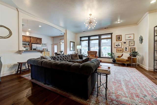 living room with dark hardwood / wood-style flooring, an inviting chandelier, and crown molding