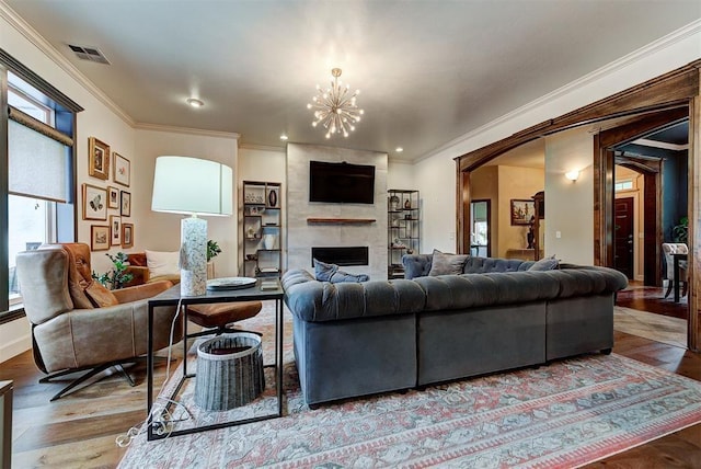 living room with a wealth of natural light, a fireplace, wood-type flooring, and a notable chandelier