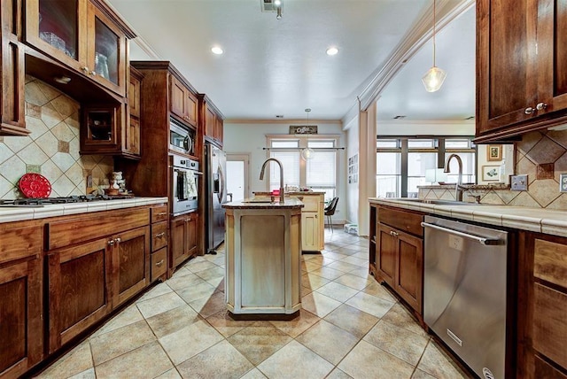 kitchen featuring stainless steel appliances, tile countertops, crown molding, decorative light fixtures, and decorative backsplash