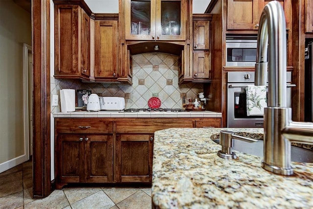 kitchen with decorative backsplash, light stone countertops, and appliances with stainless steel finishes