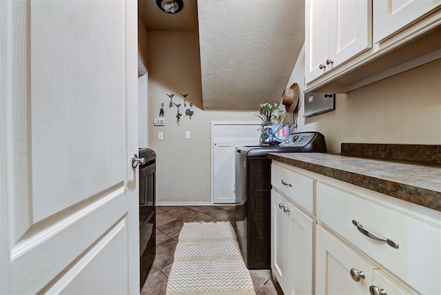 laundry room featuring washer and dryer, light tile patterned flooring, and cabinets