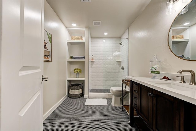 bathroom with vanity, toilet, and a tile shower