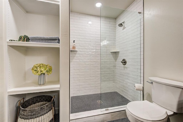 bathroom with a tile shower and toilet