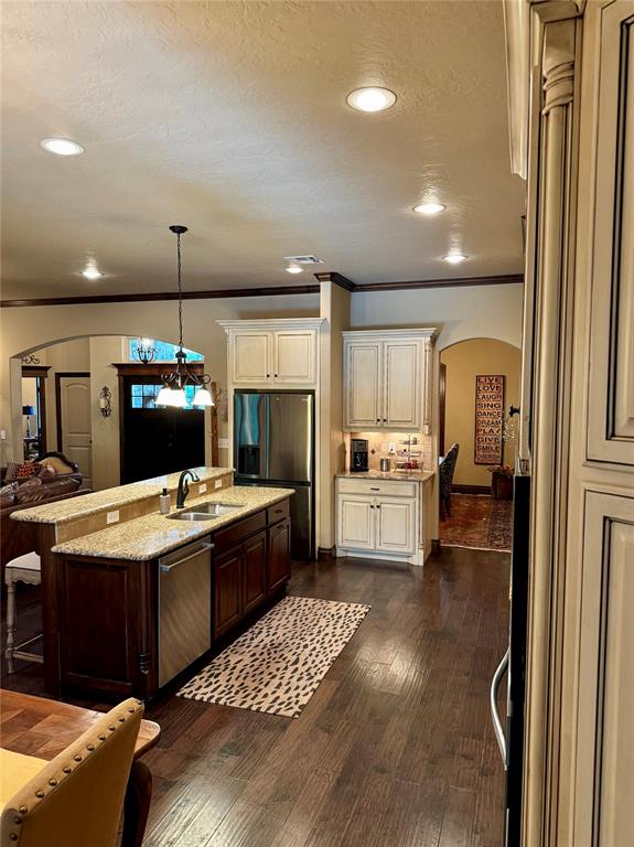 kitchen with dark wood-type flooring, hanging light fixtures, sink, appliances with stainless steel finishes, and a kitchen bar