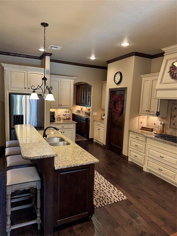 kitchen featuring a kitchen bar, light stone counters, a kitchen island with sink, dark hardwood / wood-style floors, and hanging light fixtures