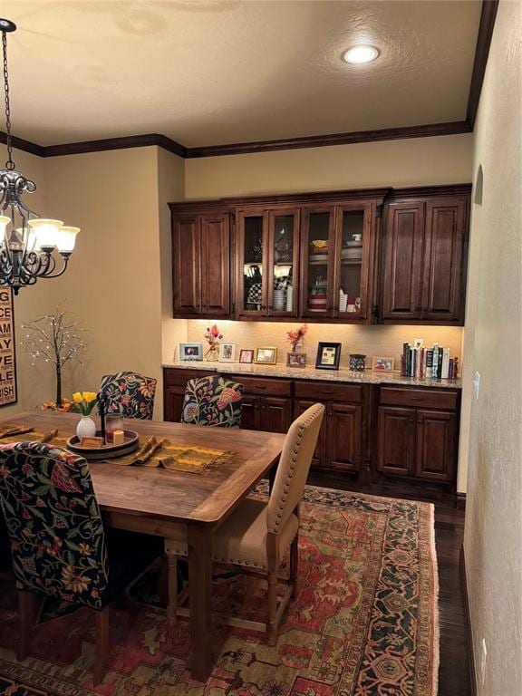 dining area featuring dark hardwood / wood-style floors, an inviting chandelier, and crown molding