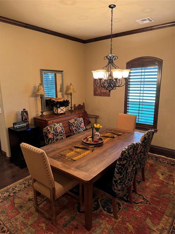 dining space featuring dark hardwood / wood-style flooring, crown molding, and an inviting chandelier