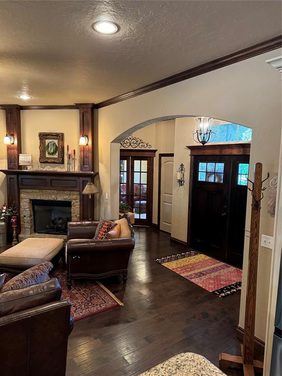 living room with a textured ceiling, a stone fireplace, plenty of natural light, and dark hardwood / wood-style floors